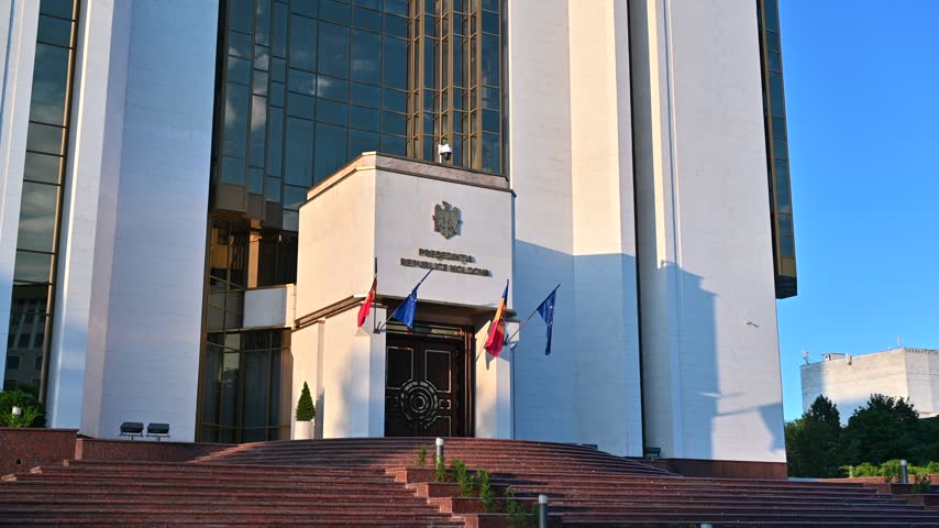 Close up shot of the presidential palace in Moldova with national and European flags waving under golden sunlight.