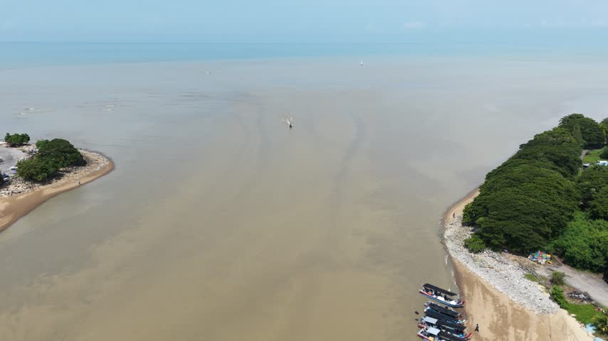 Expansive high angle view looking down across turbid river mouth waters toward distant coastal shores