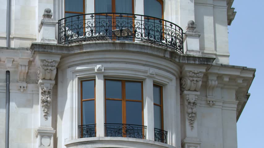 Panning down the ornate white stone facade and rounded bay windows in Geneva, Switzerland.