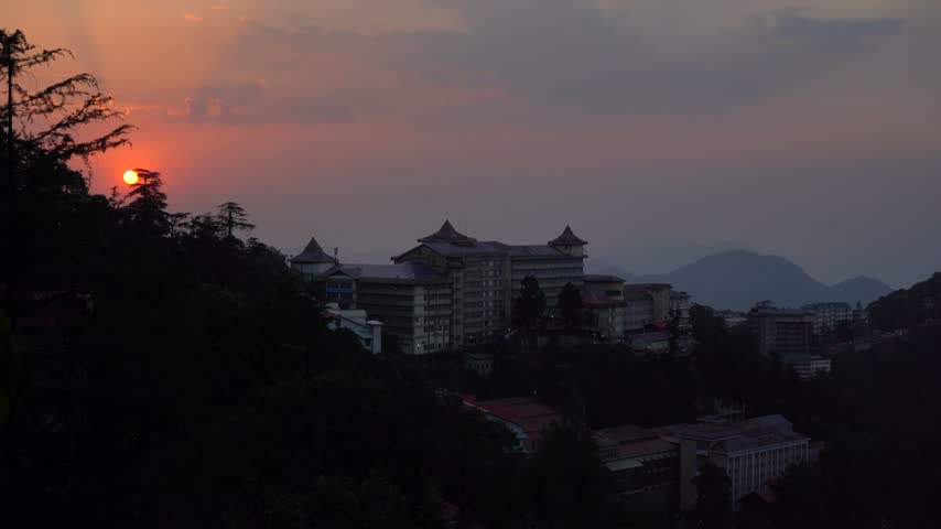 Sunset over a Himalayan mountain town with buildings and distant mountain landscape