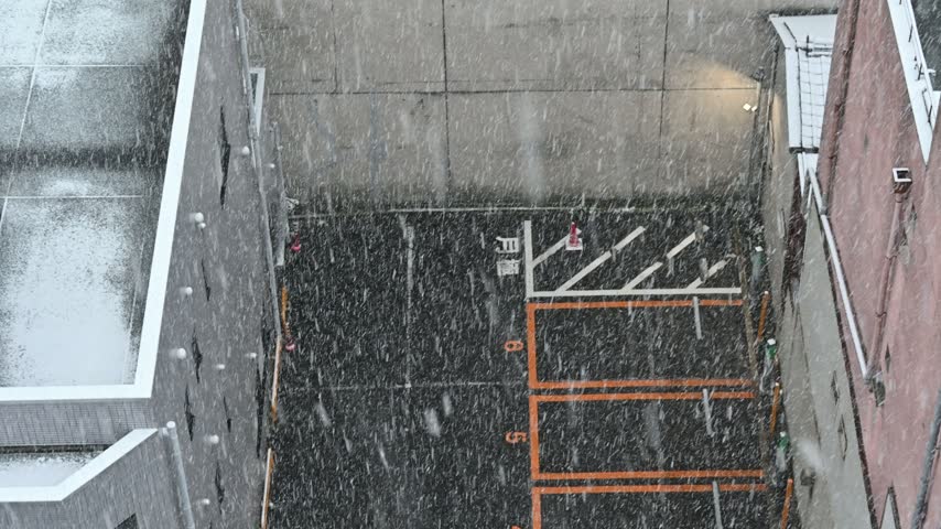 High angle view of a snowy parking lot surrounded by city buildings during winter.