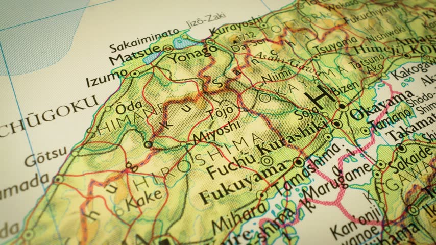 To Hiroshima, Japan – close-up of terrain and geographic features on physical map, gliding view