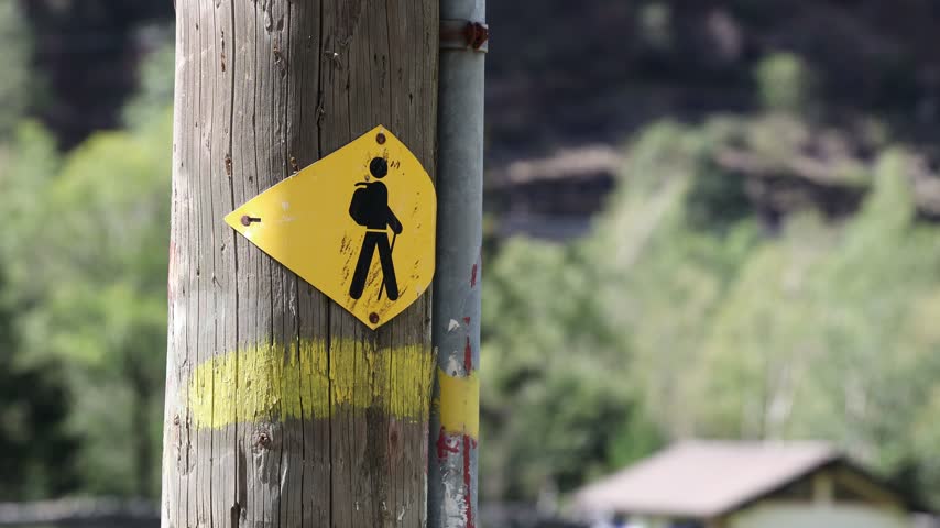 Hiking path sign on a wooden pole, isolated blurred background