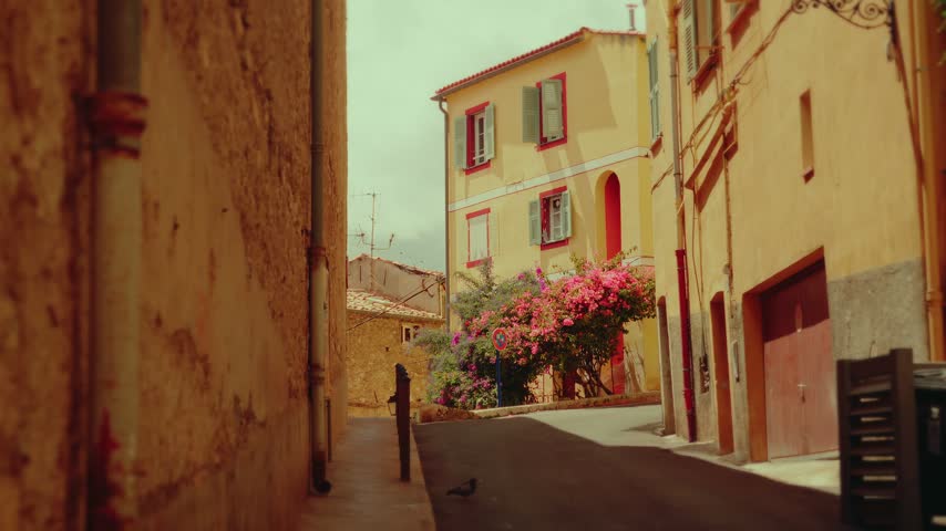 Narrow Mediterranean alleyway with vibrant yellow buildings and blooming flowers