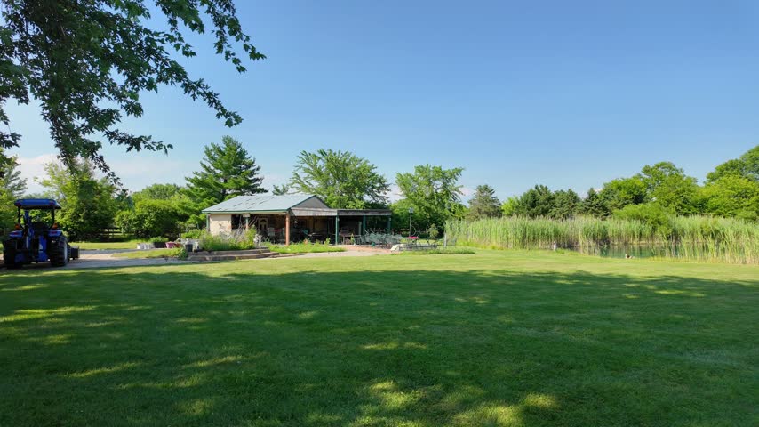 Rural midwest property with lawn, pond, and trees in Michigan on a sunny day