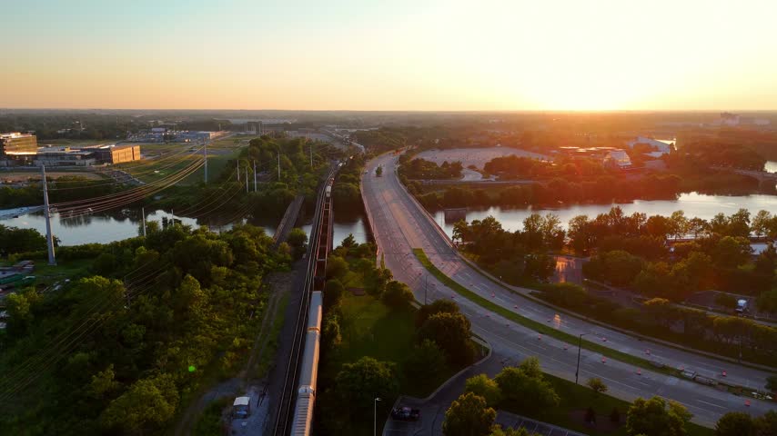 Aerial perspective of a cargo train and highway traffic crossing a river in Indianapolis