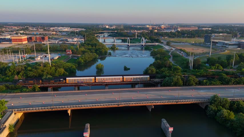 Golden hour light illuminating a freight train crossing a railway bridge over the White River in downtown Indianapolis, Indiana