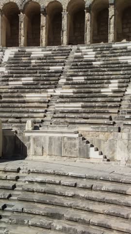 Moving view across tiered stone seats, stairways and the arched gallery of Aspendos Roman Theatre in Serik, Antalya Province, Turkey.