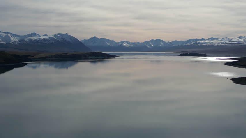New Zealand aerial view of Lake Pukaki during sunset showcases snow covered Southern Alps mountain scenery with beautiful rugged ranges and peaceful natural landscapes
