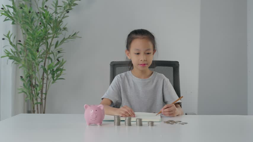 Young happy girl stacking coins on a table, learning about saving money and personal finance