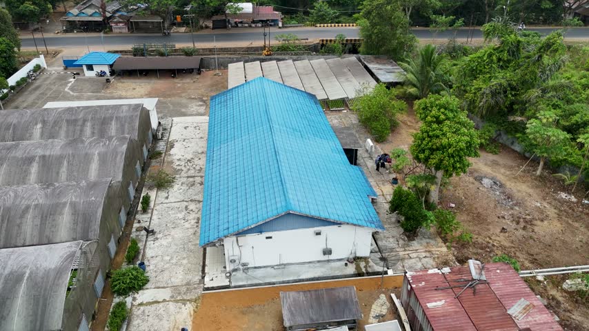 Overhead perspective of a rural warehouse building featuring a bright blue roof and solar panels