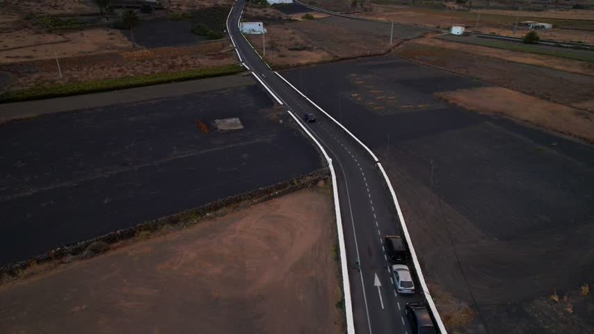 Narrow road in desertic volcanic landscape of Lanzarote. Aerial tilt up