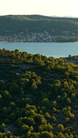 Croatia, scenic landscape of green hills, forests, and a coastal village along the blue sea