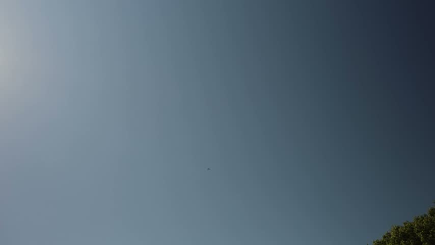 Military fighter jet flying at high altitude across a vast clear blue sky with distant aircraft silhouette creating a dramatic scene of aviation power and aerial defense missions