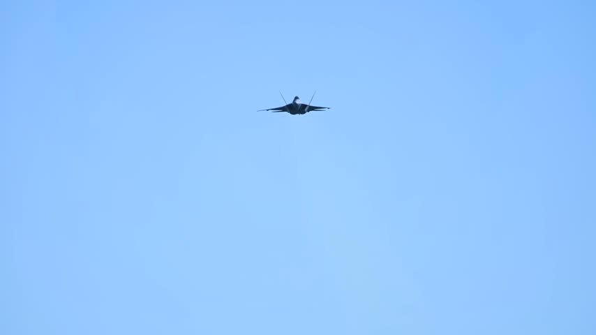 An F-22 Raptor Stealth Fighter Jet Flying Overhead Against a Solid Clear Blue Sky.