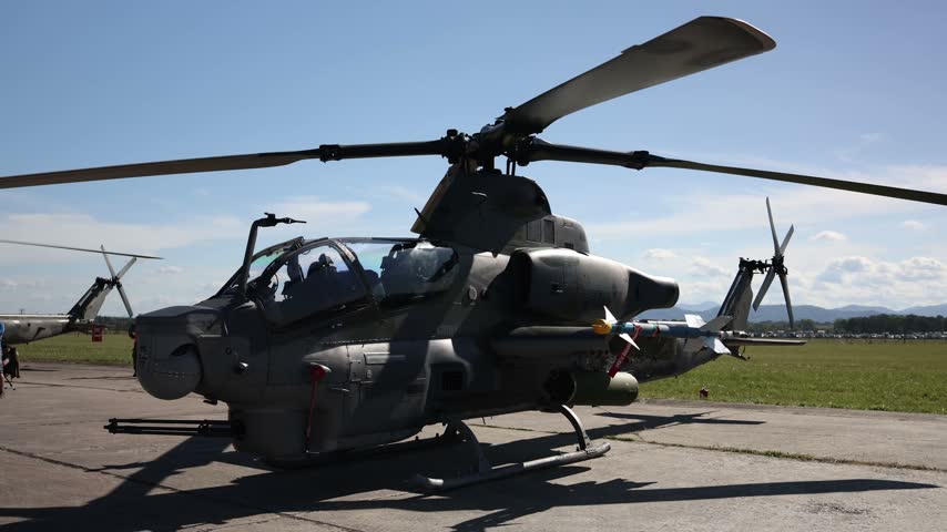 Bell AH 1Z Viper attack helicopter armed with guided missiles and a nose mounted cannon parked on an airfield showcasing modern military firepower and advanced combat aviation design
