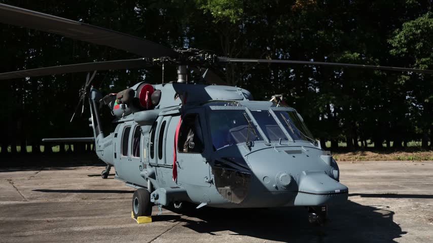 Military Sikorsky UH 60 Black Hawk helicopter parked on a concrete airfield with its rotor blades stationary showcasing a powerful utility aircraft used for tactical missions