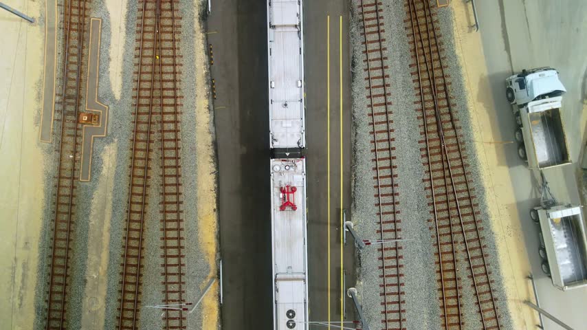 Top down view of a commuter train passing between parallel rail tracks in a maintenance depot yard