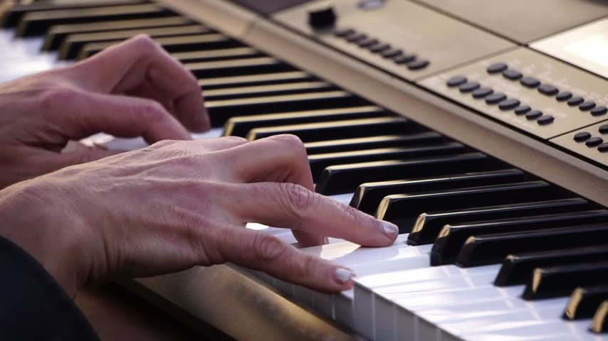 Hands playing electronic keyboard, musician performing on synthesizer, pianist fingers on keys