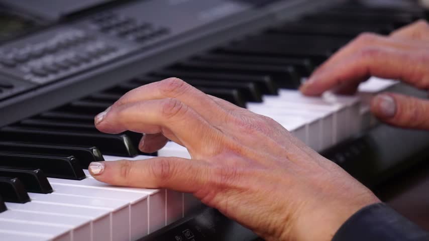 Hands playing electronic keyboard, musician performing on synthesizer, pianist fingers on keys
