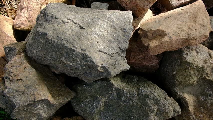 Pile of rough natural building stones and rocks stacked outdoors