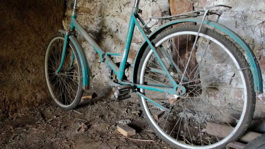 Vintage bicycle leaning against weathered stone wall inside old rural barn