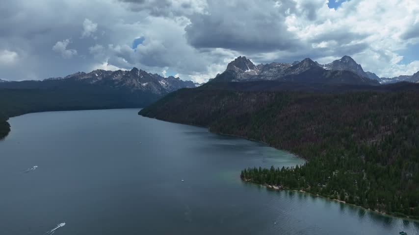 Stanley lake waters stretch toward rugged mountain peaks under a dramatic stormy sky filled with dark rolling clouds