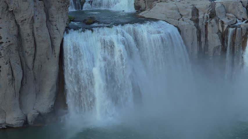 Waterfalls plunging over rocky precipices into turbulent river waters below capturing the raw power and majestic motion of rushing currents