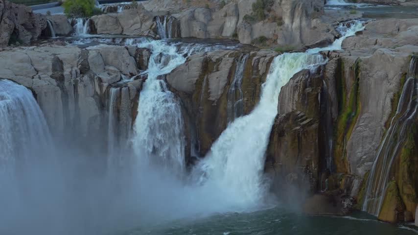 Waterfalls cascading powerfully over rugged rocky cliffs in a scenic wilderness gorge creating misty spray