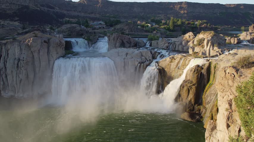 Shoshone falls cascading powerful river water over rocky cliff formations into a green pool below