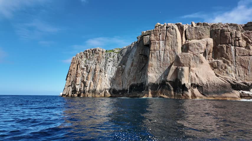 Rock island across deep blue ocean swell off the Tasman Peninsula Tasmania.