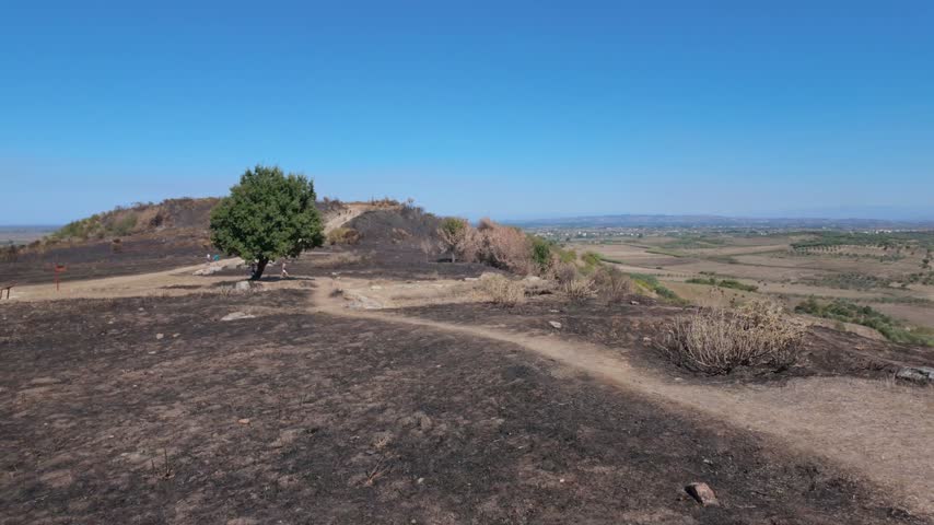 Pan shot of a burned hill top and roman ruins