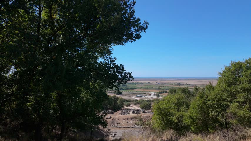 Static shot of an ancient roman theatre on the bottom of a hill with a sea view