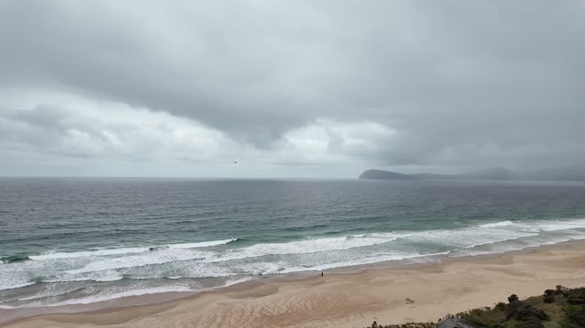 Wide curve of surf beach under storm clouds at The Neck Bruny Island Tasmania.