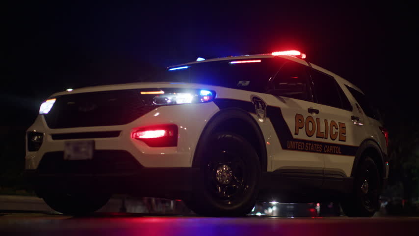 United States Capitol police car with flashing emergency lights at night.