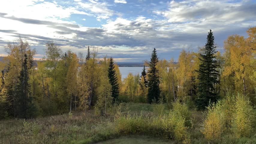 Time lapse of sunset over a lake framed by autumn forest in Alaska