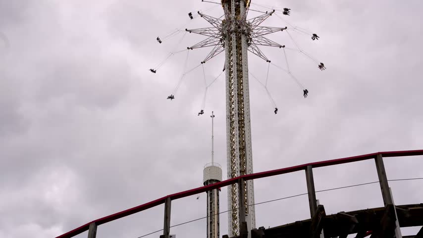 Roller coaster with grey sky in motion at amusement park.