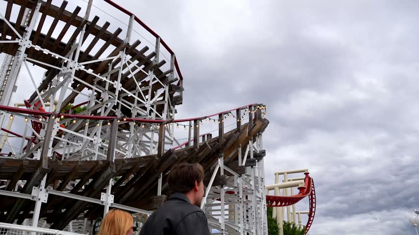 Roller coaster with grey sky in motion at amusement park.
