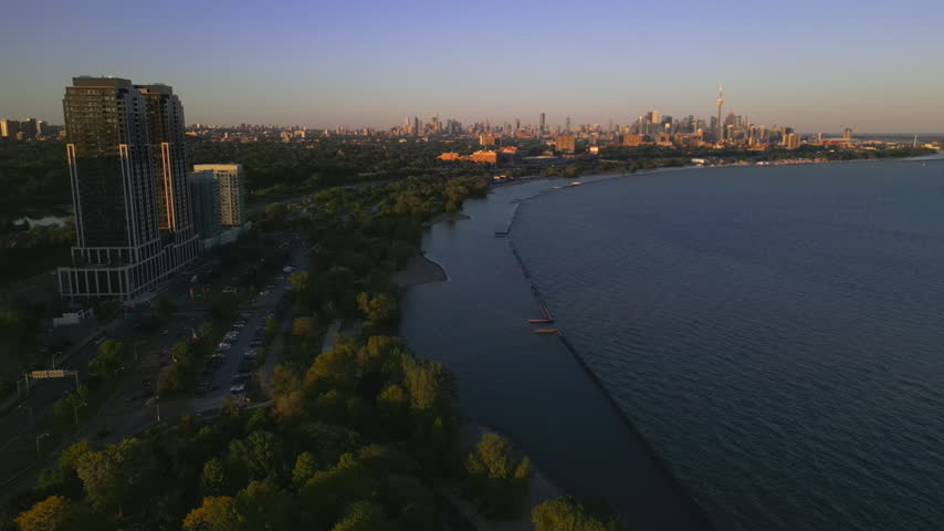 High angle aerial view of Lake Ontario coastline leading toward downtown Toronto skyline at sunset.