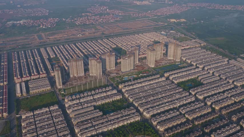 Vast aerial panorama showing extensive urban sprawl and residential development in vietnam. Morning light casts long shadows over identical houses