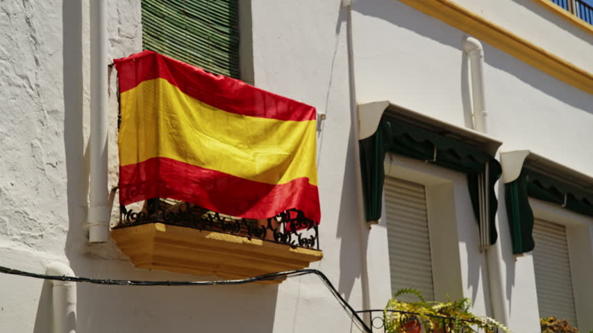 A Spanish flag on a balcony in Nijar, Andalusia, Spain. A light breeze is blowing the flag.