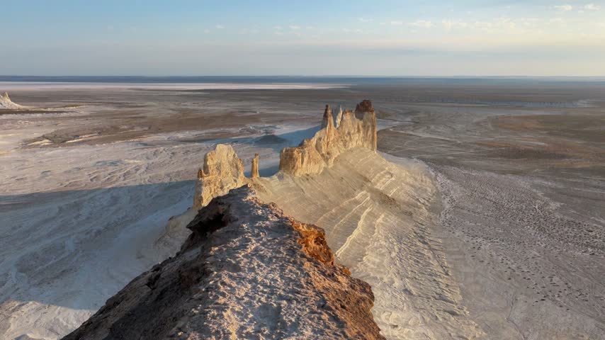 A close aerial pass follows the serrated edge of Bozzhyra Dragon Crest, emphasizing weathered pinnacles, rock texture, steep chalk slopes and the empty desert beyond.