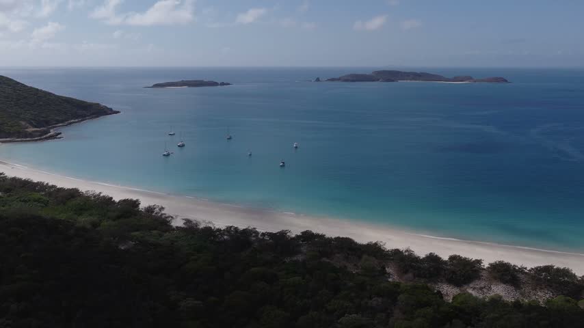 Aerial view of Keppel Islands coastline with turquoise waters and anchored boats in The Keppels, Queensland, Australia.