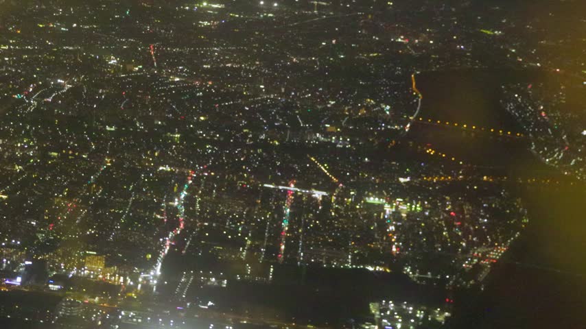 Aerial night view of illuminated streets and dense urban neighborhoods across Tokyo, Japan.