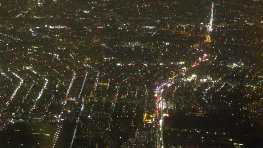Detailed aerial night view of traffic and illuminated city blocks across Tokyo, Japan.