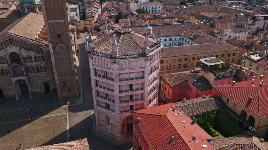 Aerial drone view of the Baptistery of Parma in Italy, showcasing its iconic octagonal design, pink marble façade, Romanesque-Gothic architecture, Piazza Duomo, and old town.