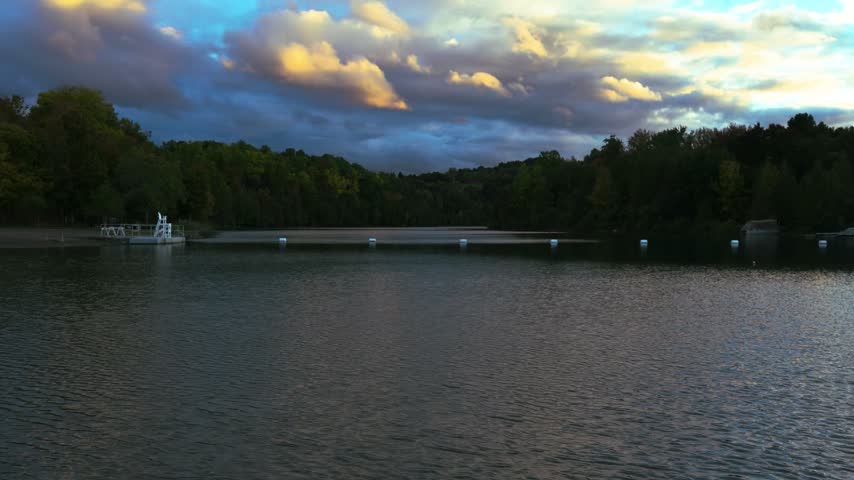 Dark clouds and warm evening light stretch across the sky above rippled water at Green Lakes State Park, New York.