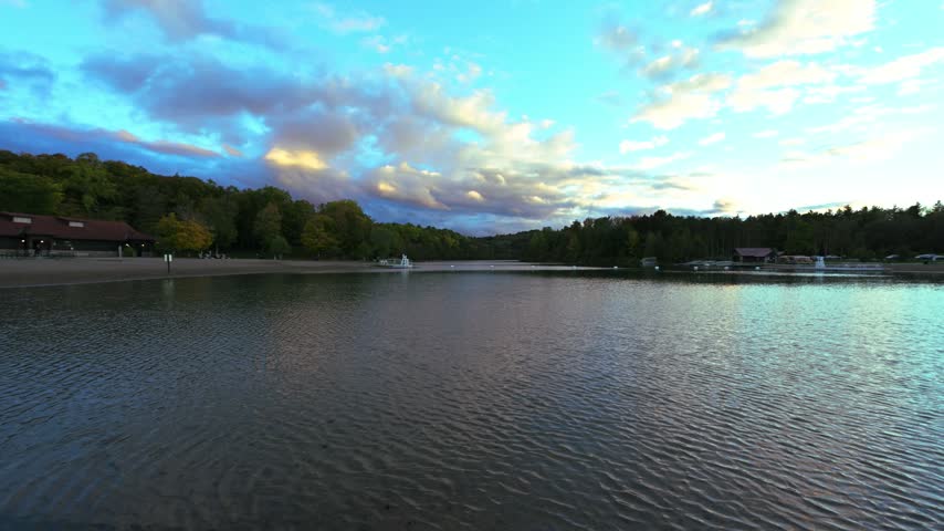 A bright blue and pink evening sky reflects in a lake bordered by trees at Green Lakes State Park in New York.