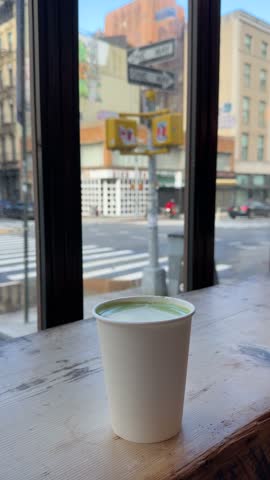 NEW YORK, USA - DECEMBER 15, 2025: Cup of coffee on cafe table near window with blurred view of Manhattan city street