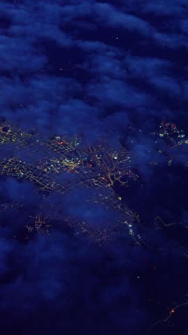 Aerial view of bogota, colombia, illuminated at night, seen from an airplane window flying over clouds